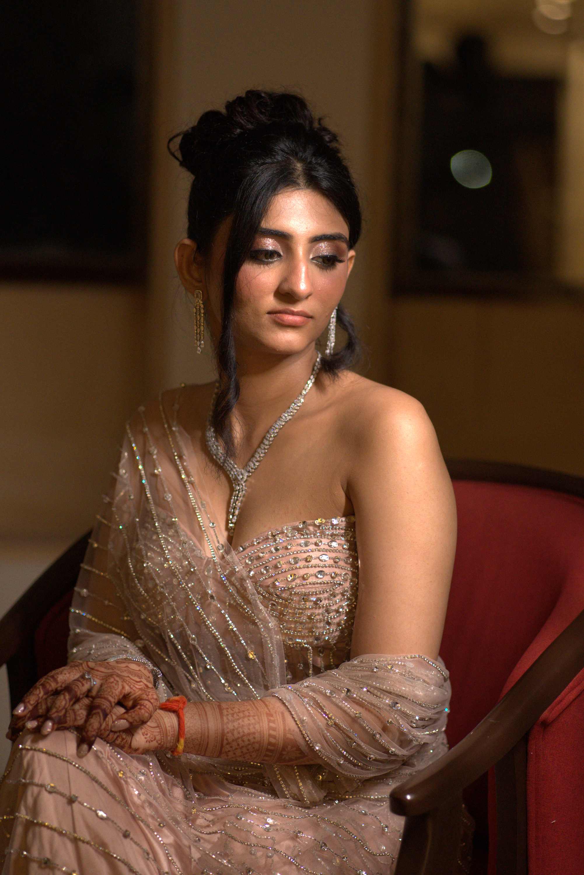 The bride seated in a sequinned saree, hands in her lap