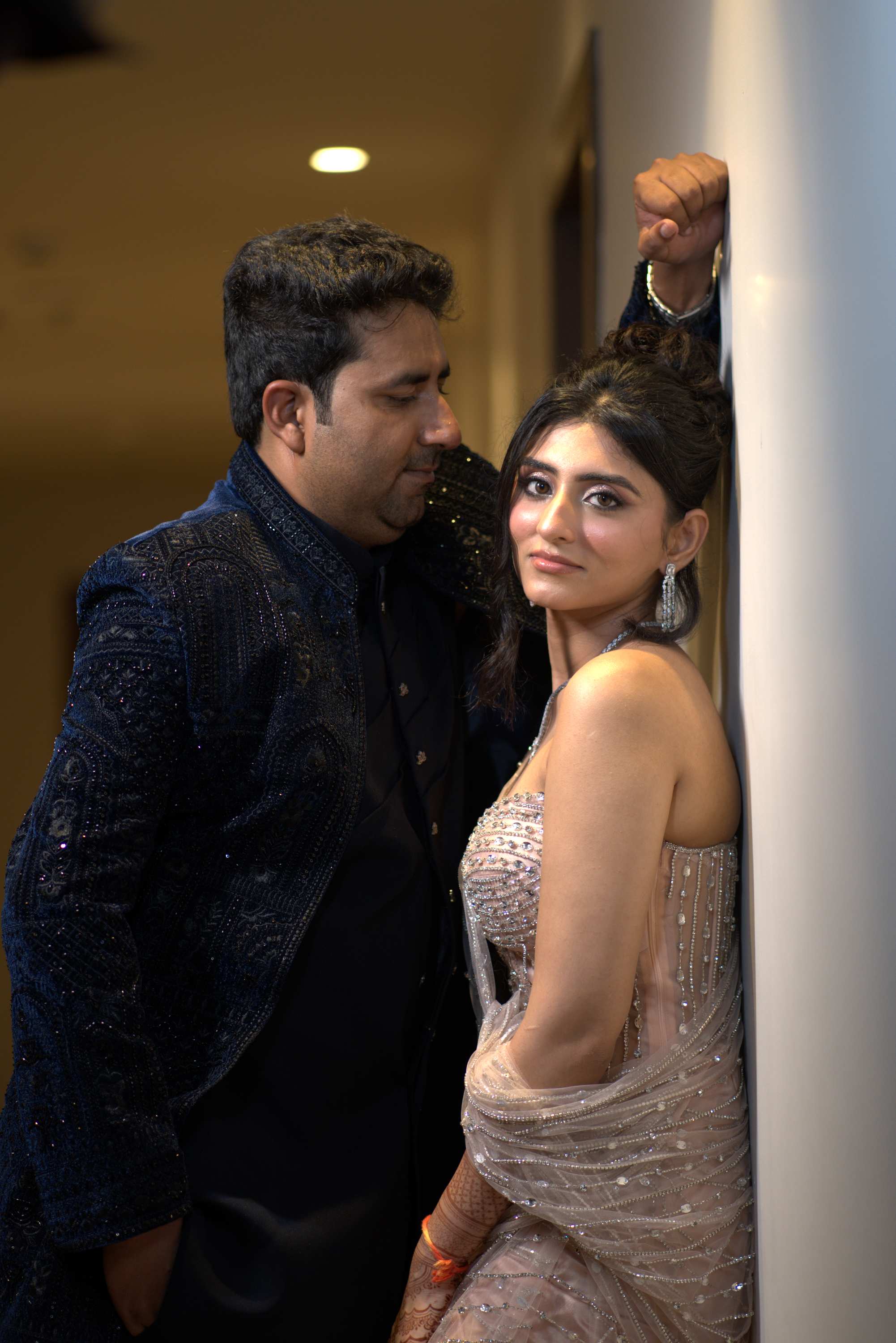 The couple beside a white pillar, one hand raised above them
