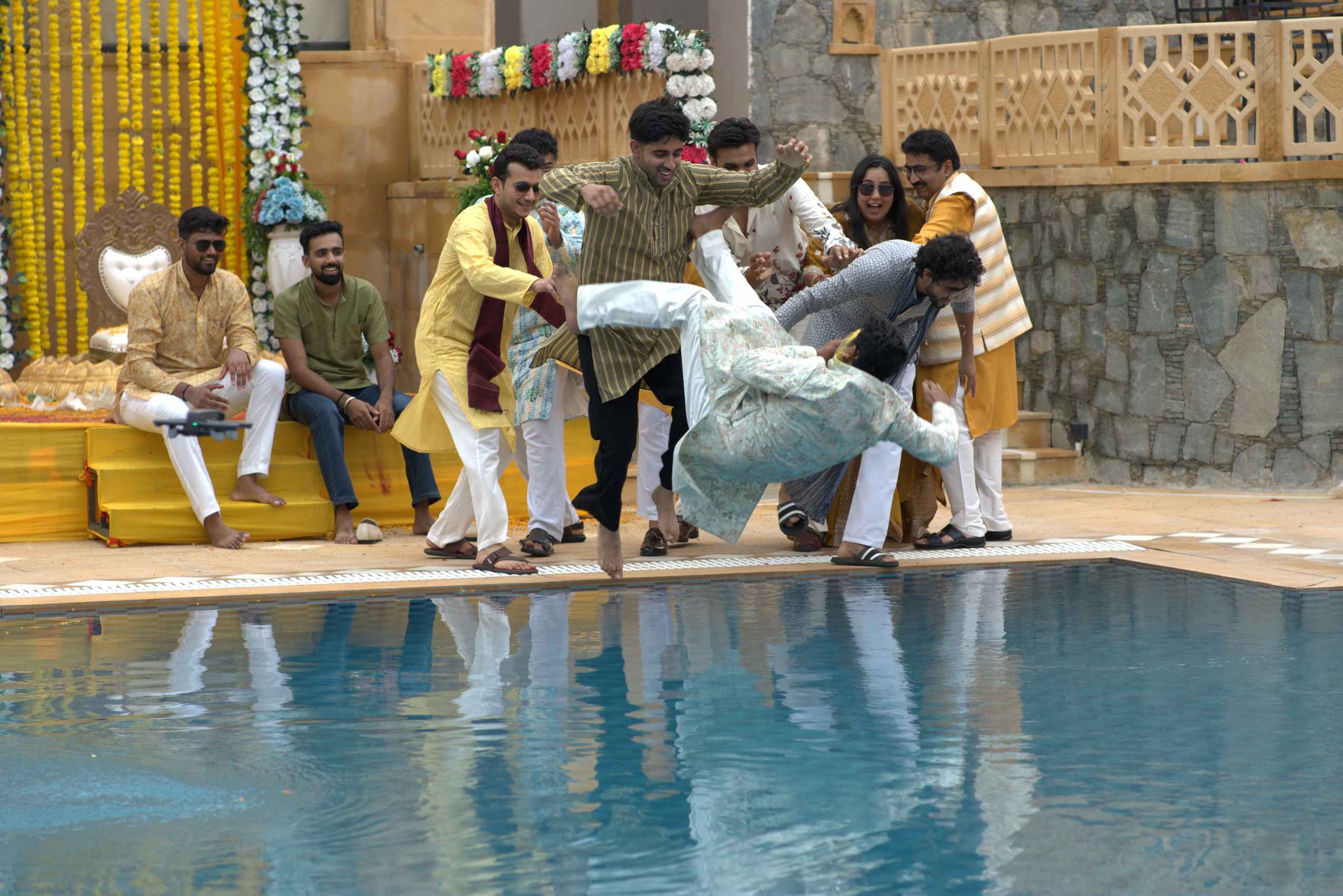 The groom going into the pool, half the party still holding on