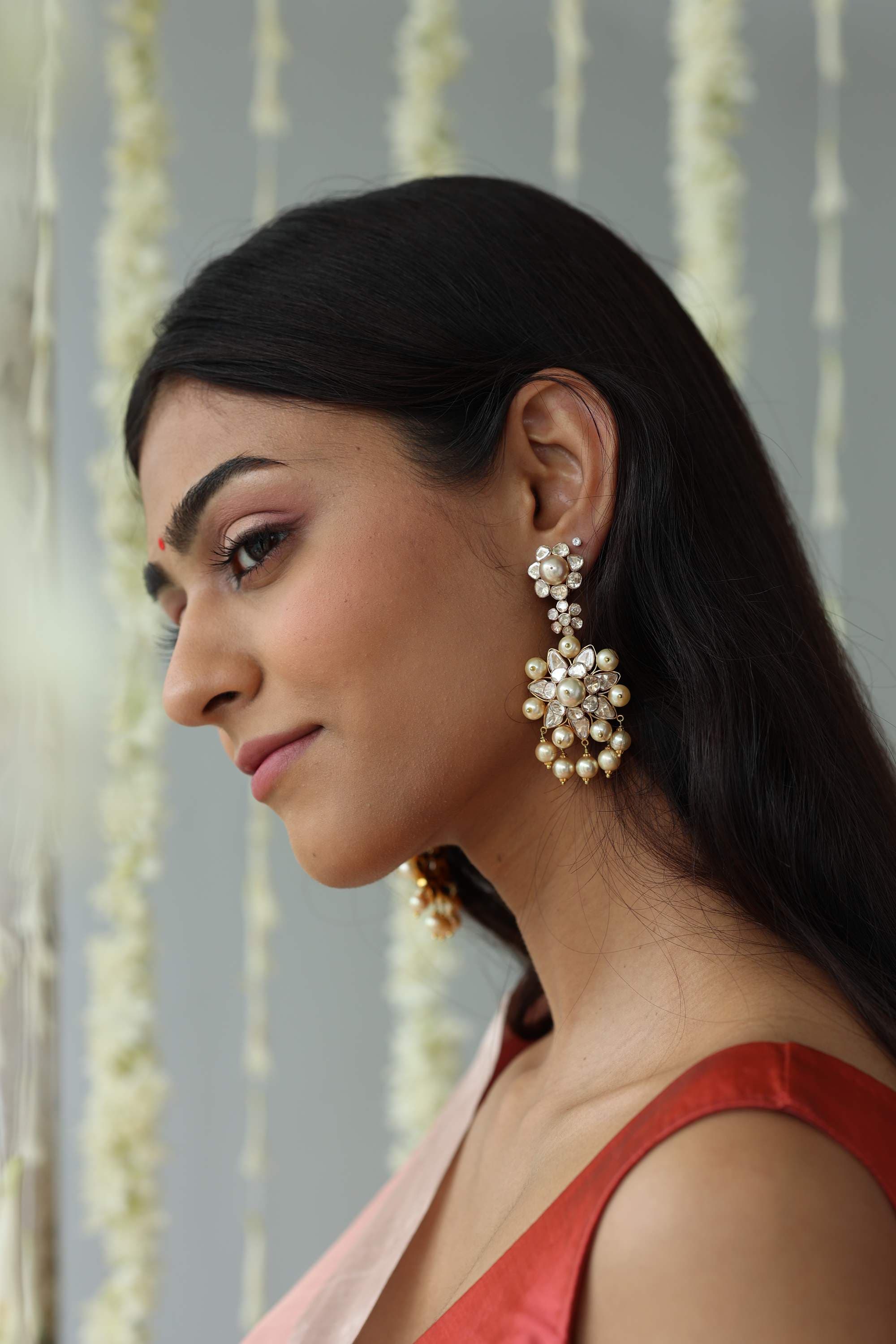 A profile in kundan floral earrings, jasmine strings behind
