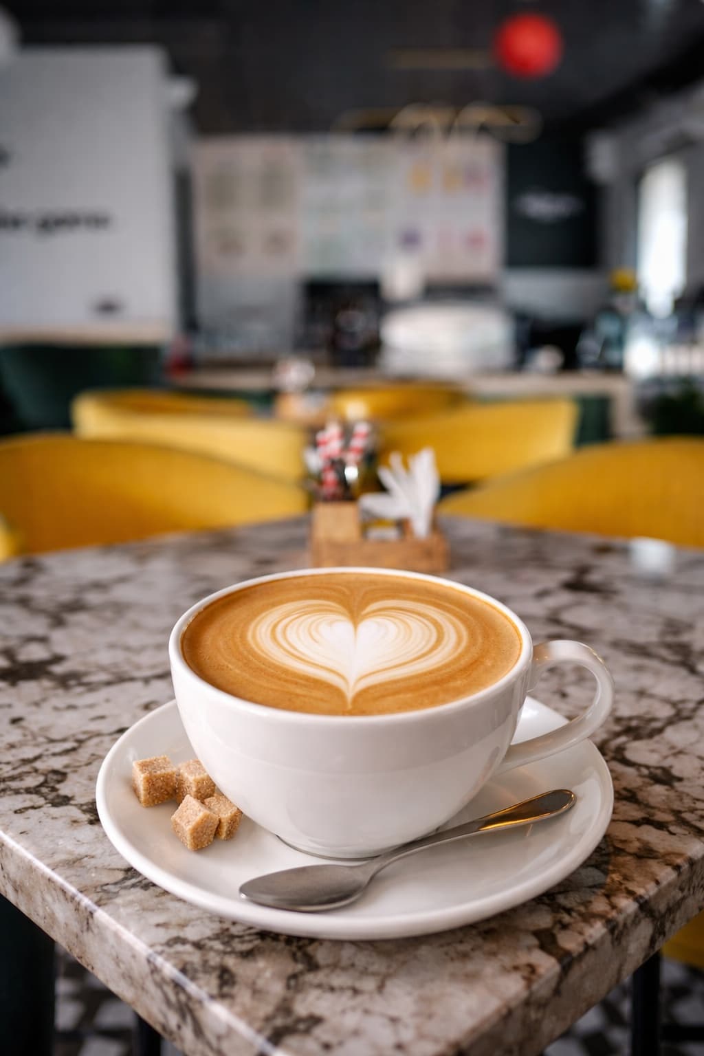 Heart latte art in a white cup on the marble table