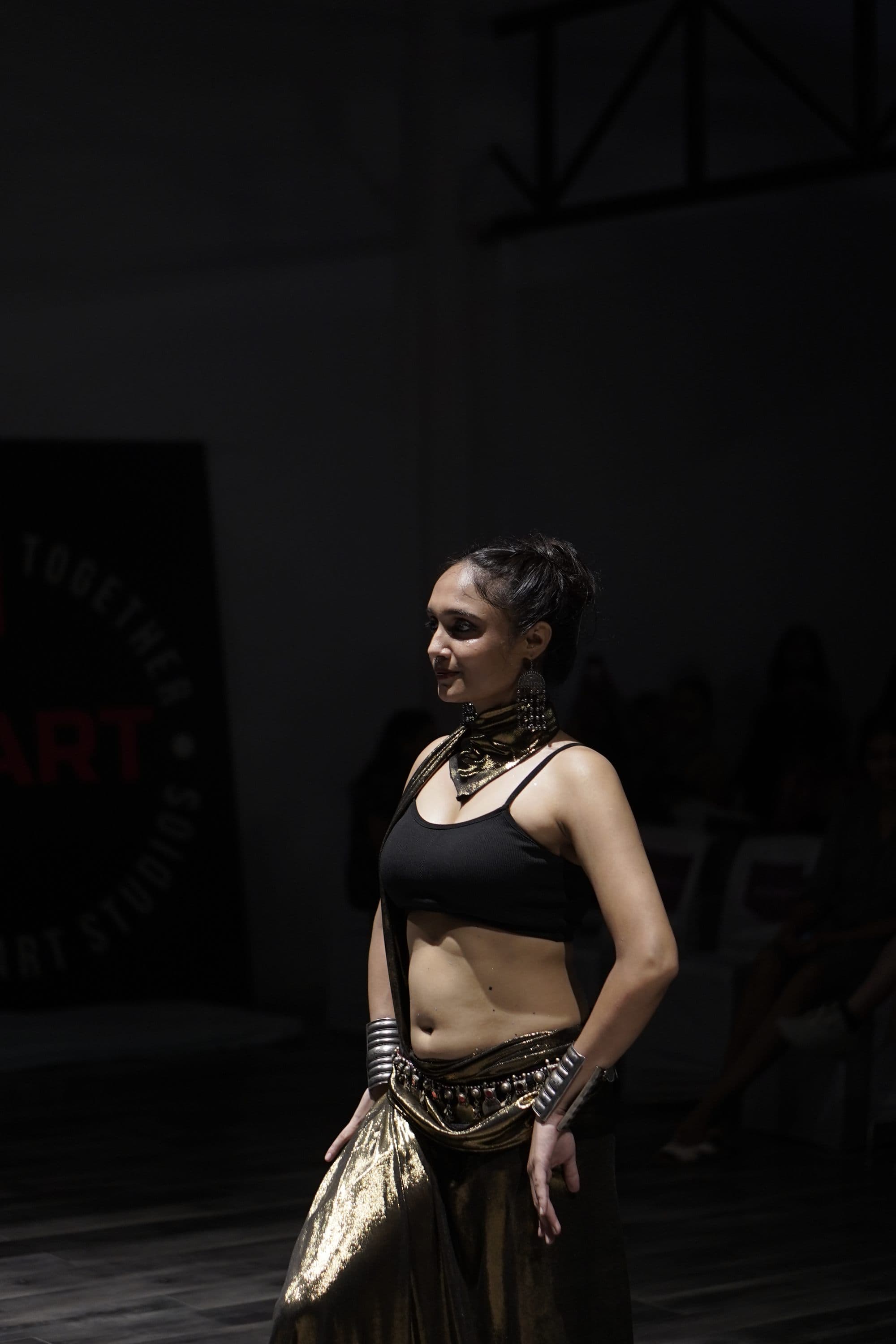 A dancer in black and gold, waiting at the edge of the stage
